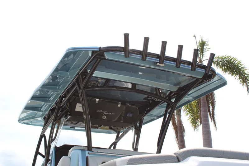 Slide: The Image of 2021 Nor-Tech 390 Sport Center Console boat with T-top and rod holders, palm trees in background. - 24
