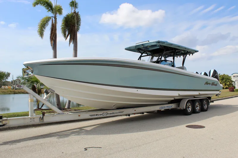 Slide: The Image of 2021 Nor-Tech 390 Sport Center Console boat on trailer, parked near palm trees. - 3