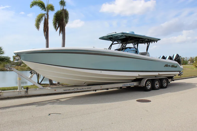 Slide: The Image of 2021 Nor-Tech 390 Sport Center Console boat on trailer, parked near palm trees. - 4