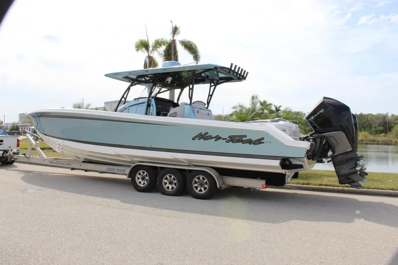 Slide: The Image of 2021 Nor-Tech 390 Sport Center Console boat on trailer, parked near palm trees. - 8
