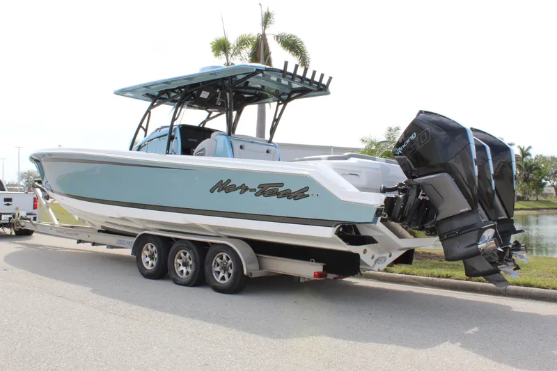 Slide: The Image of 2021 Nor-Tech 390 Sport Center Console boat on trailer, parked near palm trees. - 9