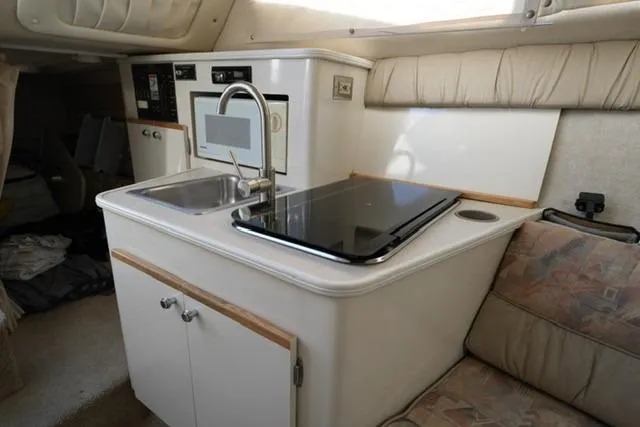Slide: The Image of 1999 Bayliner 2655 Ciera Sunbridge interior with kitchenette, sink, and seating area. - 20