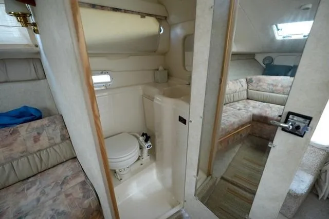 Slide: The Image of 1999 Bayliner 2655 Ciera Sunbridge interior with compact bathroom and cozy seating area. - 21