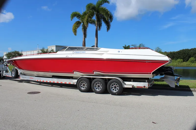 Slide: The Image of 2007 Fountain 42 Lightning speedboat on trailer, red and white, parked near palm trees. - 3