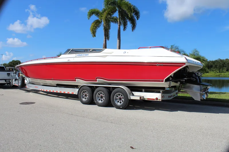 Slide: The Image of 2007 Fountain 42 Lightning boat on trailer, red and white, parked near palm trees. - 4