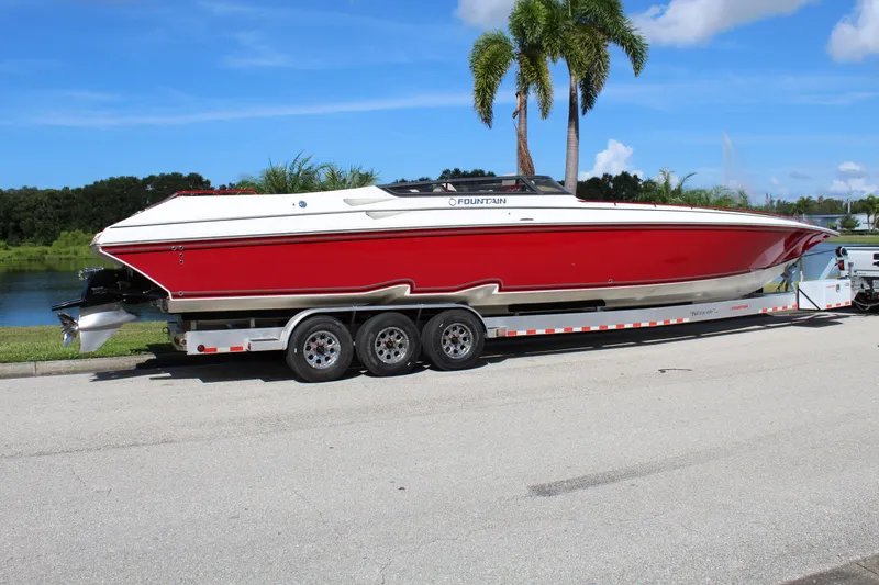 Slide: The Image of 2007 Fountain 42 Lightning speedboat on trailer, red and white, parked near palm trees. - 8