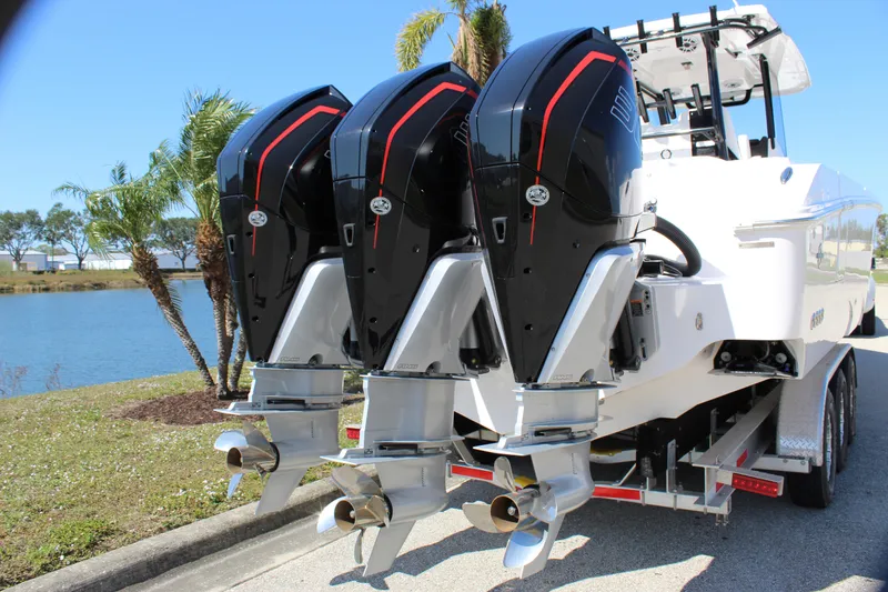 Slide: The Image of 2024 Fountain 32 NX boat with triple outboard engines, parked near a lake. - 22