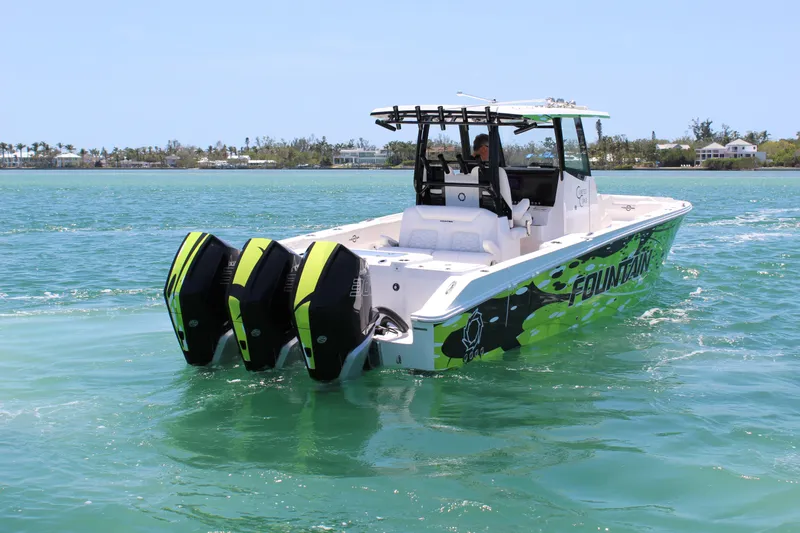 Slide: The Image of 2024 Fountain 32 NX boat with triple outboard engines cruising on clear blue water. - 5