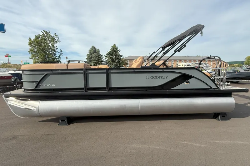 Slide: The Image of 2026 Godfrey SWEETWATER 2286 SFL pontoon boat with canopy, parked outdoors. - 2