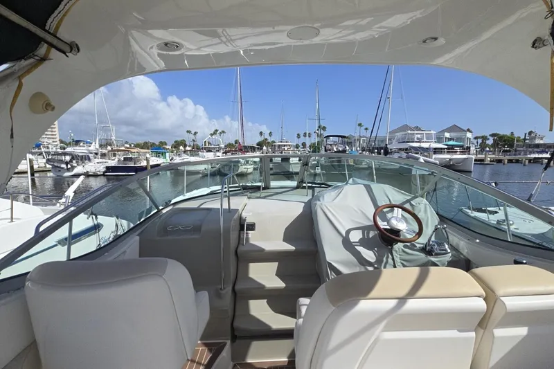Slide: The Image of 2010 Sea Ray 350 Sundancer yacht interior at marina, showcasing helm and seating area. - 14