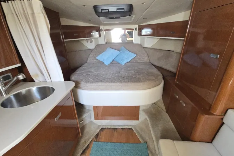 Slide: The Image of 2010 Sea Ray 350 Sundancer cabin interior with bed, sink, and wooden cabinetry. - 2