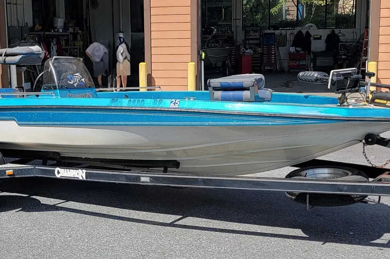 Slide: The Image of 1995 Champion 181 SC boat on trailer outside a garage. - 3