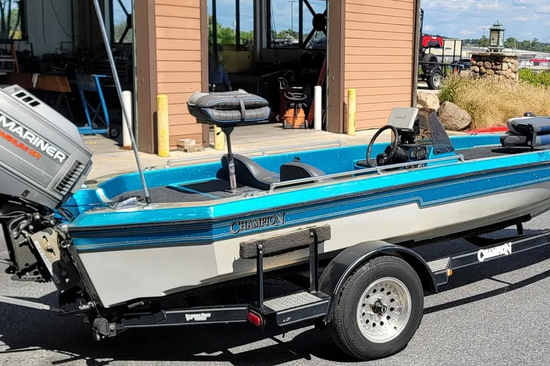 Slide: The Image of 1995 Champion 181 SC boat with Mariner engine on a trailer, parked outside a garage. - 4