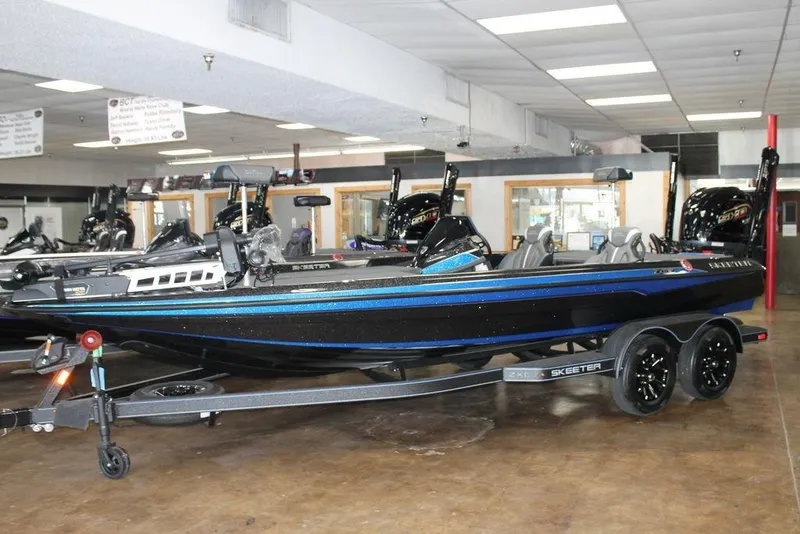 Slide: The Image of 2026 Skeeter ZXE21 boat in showroom, black and blue design, on trailer. - 1