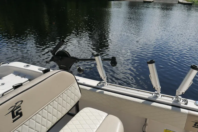 Slide: The Image of 2022 Carolina Skiff 23 Ultra Elite boat interior with rod holders on a calm lake. - 17