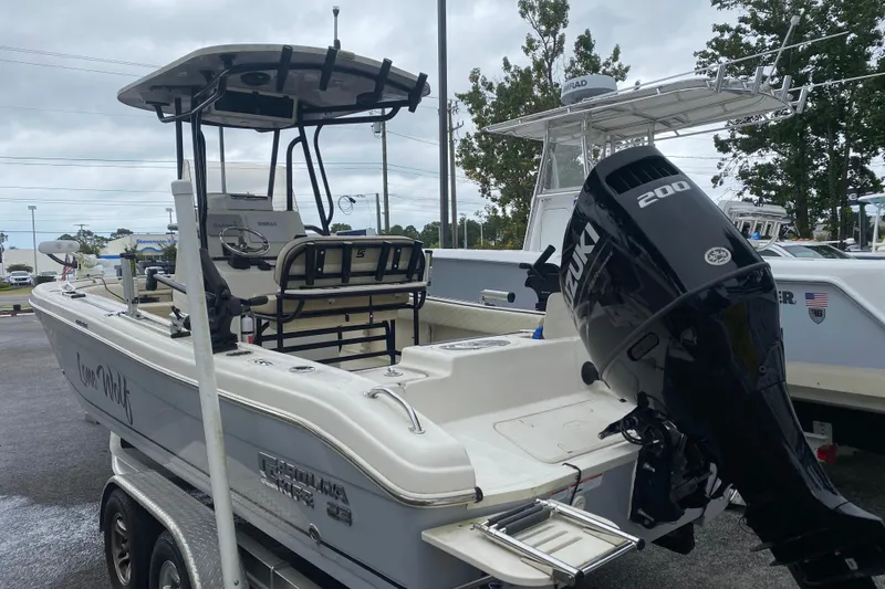 Slide: The Image of 2022 Carolina Skiff 23 Ultra Elite boat on a serene lake with lush greenery. - 2