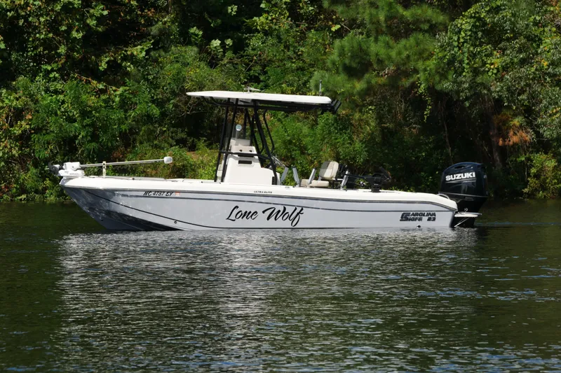 Slide: The Image of 2022 Carolina Skiff 23 Ultra Elite boat on a calm river, surrounded by lush greenery. - 3