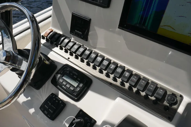 Slide: The Image of Control panel of 2022 Carolina Skiff 23 Ultra Elite boat with switches and steering wheel. - 31
