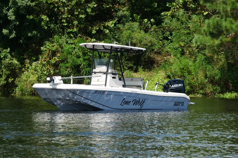 Slide: The Image of 2022 Carolina Skiff 23 Ultra Elite boat on water, surrounded by lush greenery. - 4