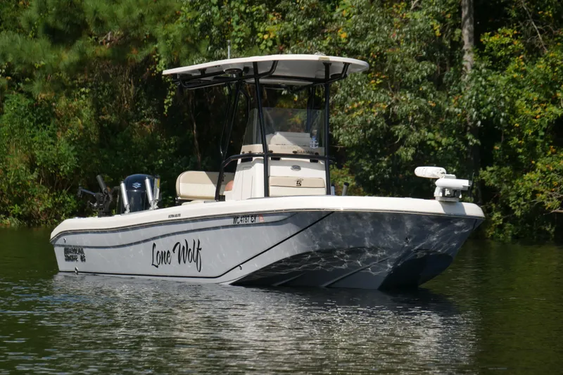 Slide: The Image of 2022 Carolina Skiff 23 Ultra Elite boat named "Lone Wolf" on a serene lake. - 6