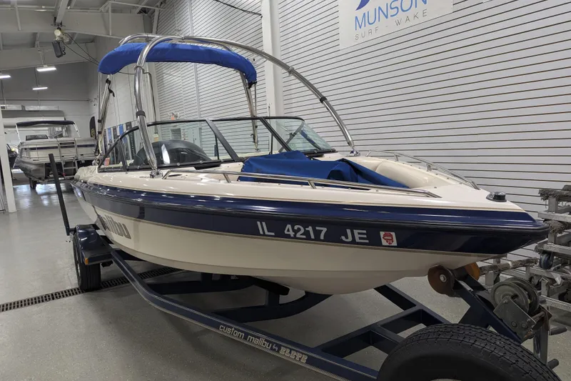 Slide: The Image of 1998 Malibu Sunsetter VLX boat on trailer in showroom, blue and white design. - 14