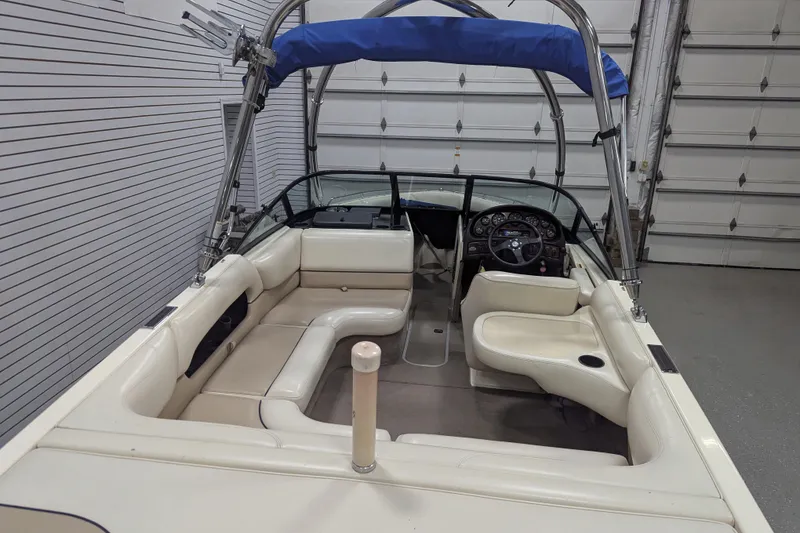 Slide: The Image of 1998 Malibu Sunsetter VLX boat interior with white seating and blue canopy in a garage. - 17