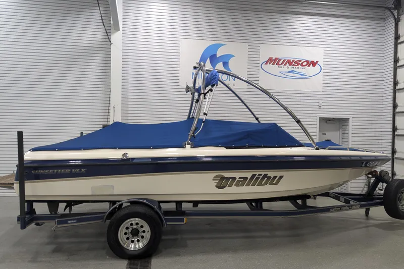 Slide: The Image of 1998 Malibu Sunsetter VLX boat with blue cover on trailer in showroom. - 26