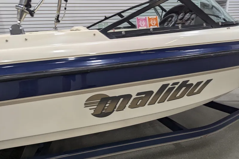 Slide: The Image of 1998 Malibu Sunsetter VLX boat with blue and white design in showroom. - 5
