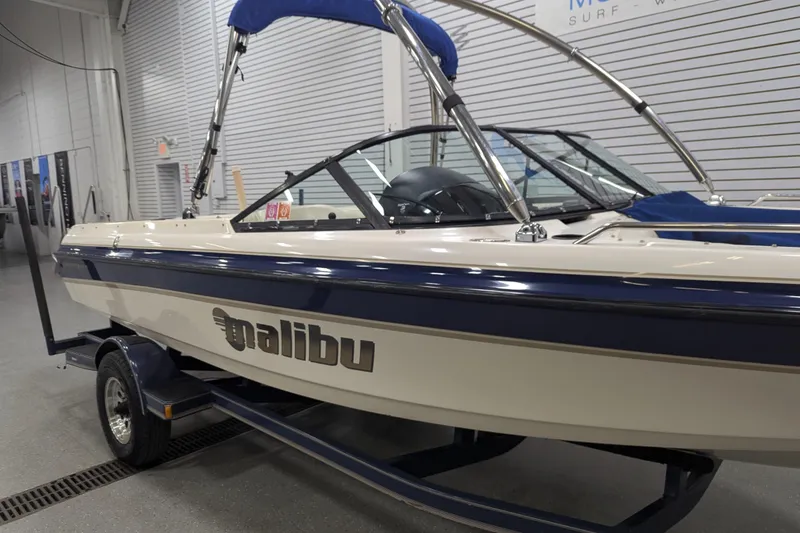 Slide: The Image of 1998 Malibu Sunsetter VLX boat with blue accents in a showroom. - 6