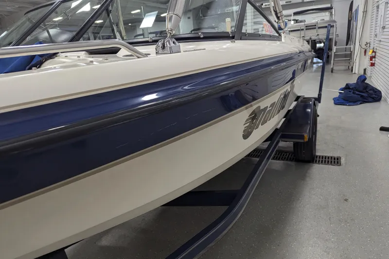 Slide: The Image of 1998 Malibu Sunsetter VLX boat in a garage, showcasing sleek design and blue accents. - 8