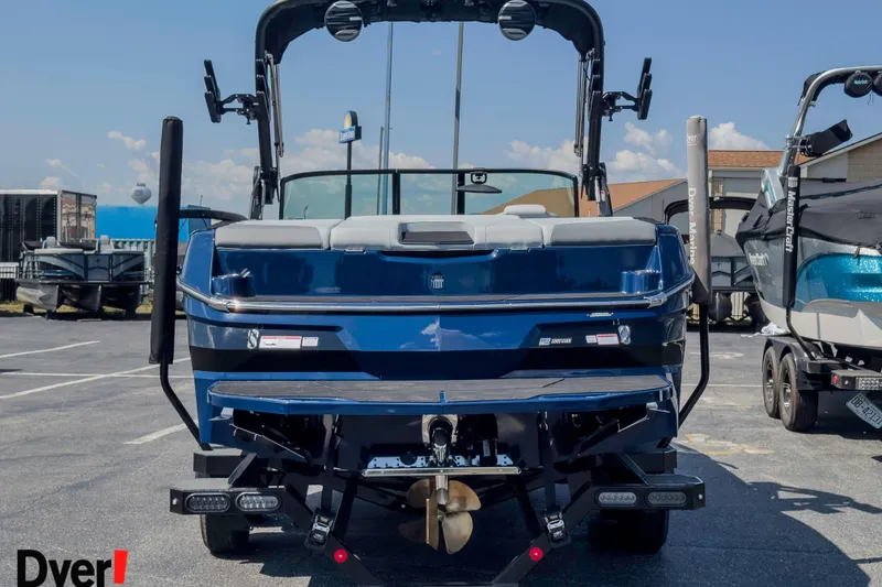 Slide: The Image of 2026 MasterCraft NXT22 boat, rear view, parked outdoors on a sunny day. - 2