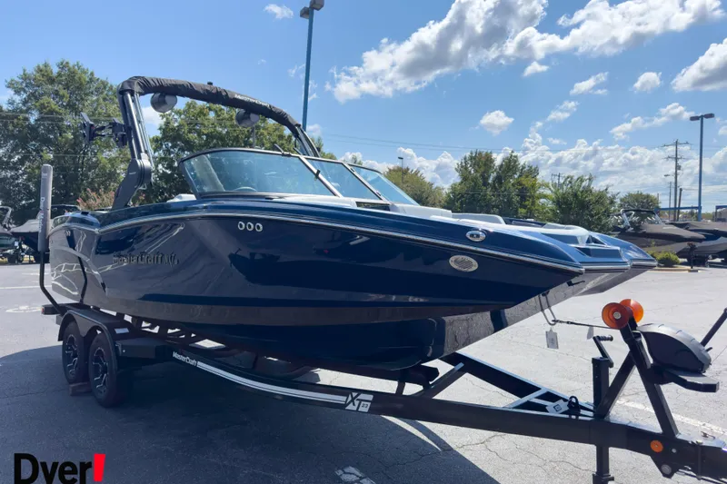 Slide: The Image of 2026 MasterCraft NXT22 boat on trailer under a clear blue sky. - 5