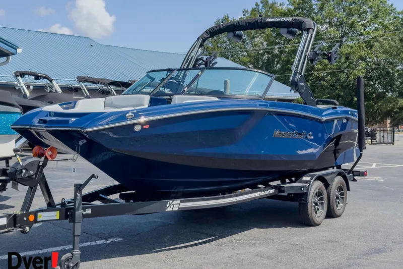 Slide: The Image of 2026 MasterCraft NXT22 boat in blue on a trailer, parked outdoors. - 6