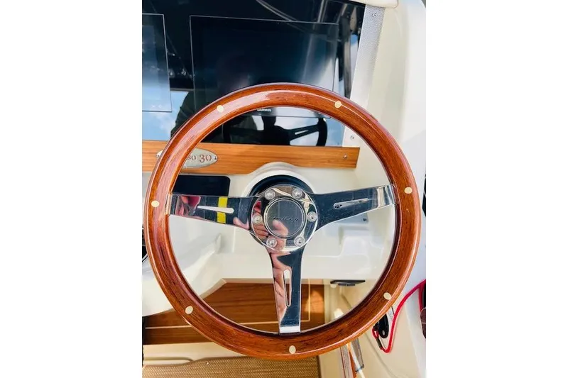 Slide: The Image of Steering wheel of 2022 Chris-Craft Calypso 30 boat, featuring wood and chrome design. - 27