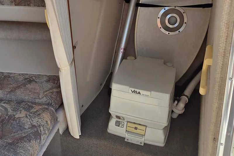 Slide: The Image of 1998 Maxum 2300 SC cabin interior with portable toilet and seating area. - 13
