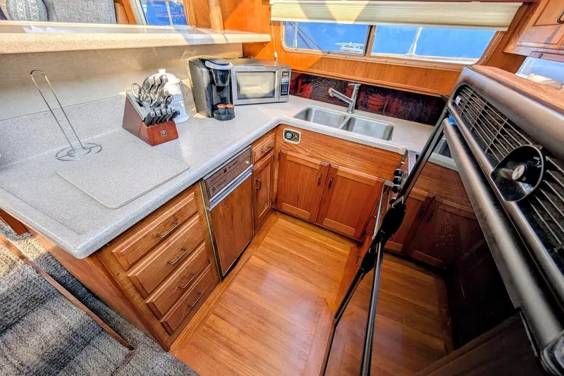 Slide: The Image of 1978 Tollycraft 54 Custom Cockpit Motor Yacht kitchen with wooden cabinets and modern appliances. - 23