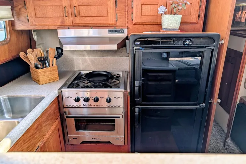 Slide: The Image of 1978 Tollycraft 54 yacht kitchen with stove, fridge, and wooden cabinets. - 27