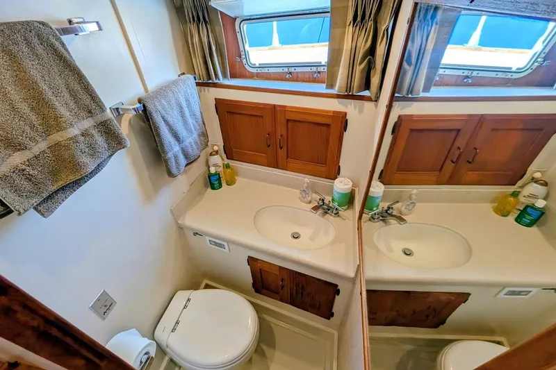 Slide: The Image of 1978 Tollycraft 54 Custom Cockpit Motor Yacht bathroom with sink, mirror, and wooden cabinets. - 35