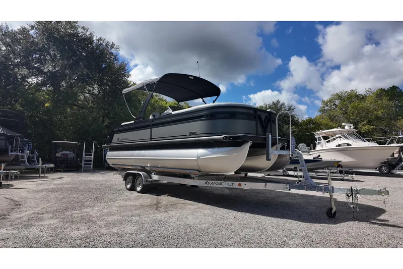 Slide: The Image of 2026 Viaggio Lago X22U pontoon boat on trailer, parked outdoors under a cloudy sky. - 2