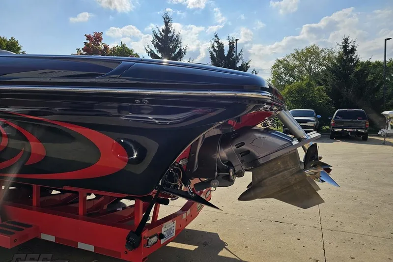 Slide: The Image of 2011 Sunsation F-4 boat on trailer, featuring sleek black and red design, under sunny sky. - 31