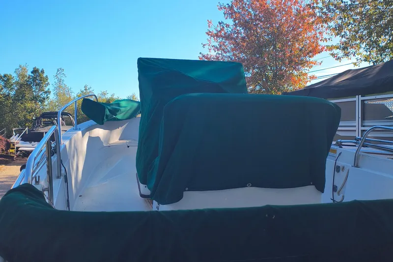 Slide: The Image of 2002 Boston Whaler 180 Dauntless boat with green covers, parked outdoors. - 5