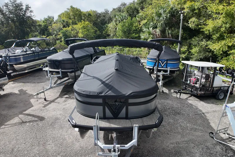 Slide: The Image of 2026 Viaggio Diamante D22S pontoon boat covered, parked outdoors with other boats. - 6