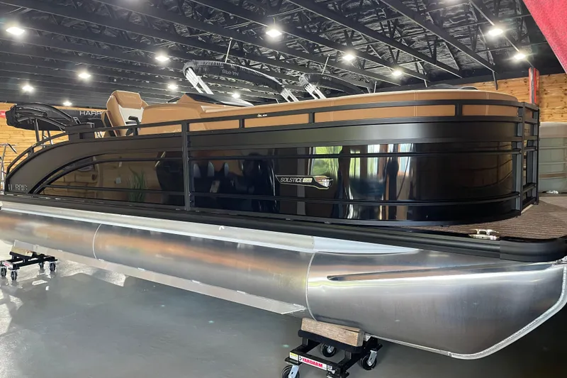 Slide: The Image of 2026 Harris Solstice 230 pontoon boat displayed indoors, featuring sleek black design. - 1