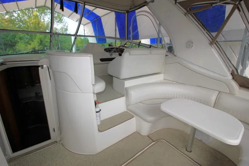 Slide: The Image of 2000 Cruisers Yachts 3672 Express interior with white seating and table under canopy. - 6