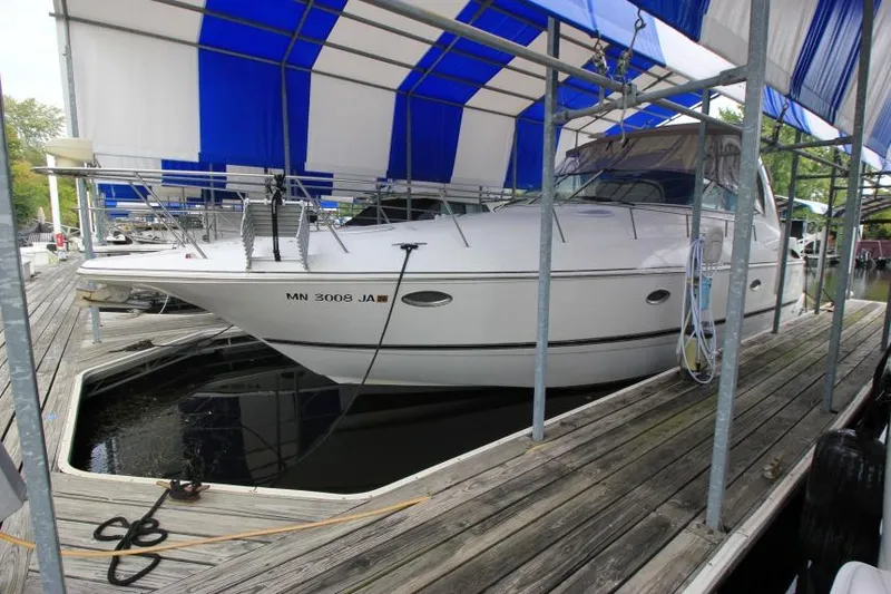 Slide: The Image of 2000 Cruisers Yachts 3672 Express docked under blue and white canopy. - 1