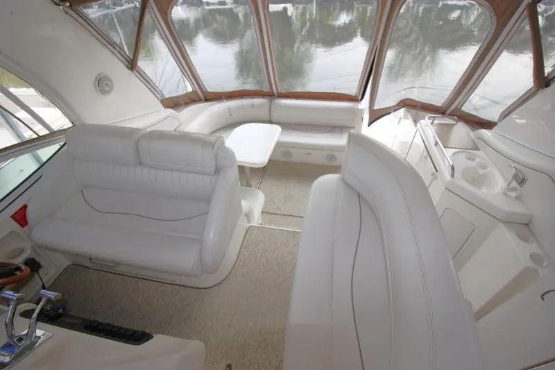 Slide: The Image of 2000 Cruisers Yachts 3672 Express interior with white seating and table, featuring panoramic windows. - 11