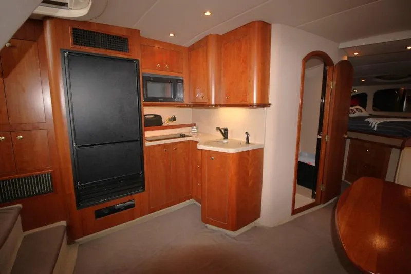 Slide: The Image of 2000 Cruisers Yachts 3672 Express interior with wood cabinetry and compact kitchen area. - 13