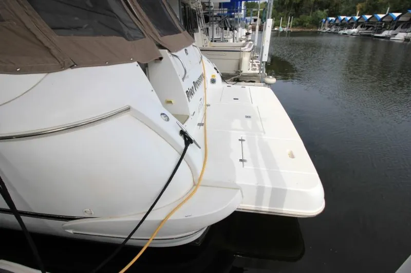 Slide: The Image of 2000 Cruisers Yachts 3672 Express docked at marina, rear view with water backdrop. - 2