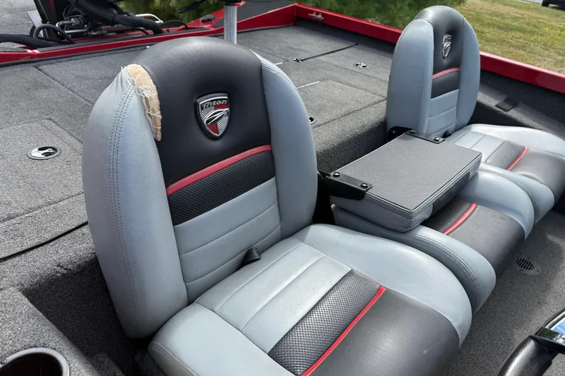 Slide: The Image of 2018 Triton 18 TX boat seats with wear, featuring gray and black upholstery with red accents. - 10