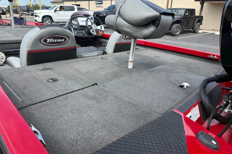 Slide: The Image of 2018 Triton 18 TX boat interior with seating and control panel, parked in a lot. - 12